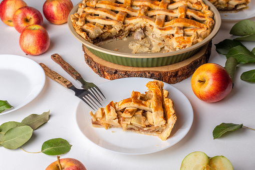 a slice of apple pie on a plate, ready to eat. Thanksgiving traditional dessert with red and green apples, Thanksgiving tart preparation, autumn bakery. Food lifestyle, recipe