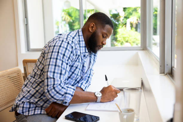 istock Handsome black man drinking smoothie and working at laptop in kitchen 1830977673