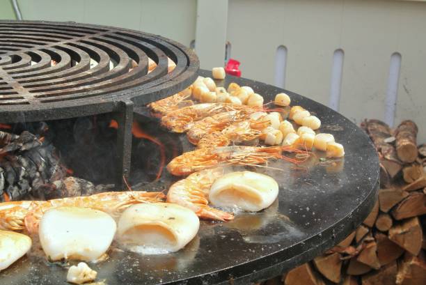 istock Seafood slices are cooked on a fire pit surface in the shape of cone shaped bowl. Bowl-shaped flat grill with squid and prawn. Outdoor barbecue cooking. Street food concept. Toast the hot grilled 1831015143