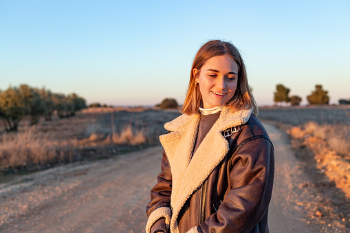 Castilla La Mancha, Spain. The scene suggests a moment of joy in harmony with the natural beauty surrounding the young woman in the tranquility of the countryside at sunset