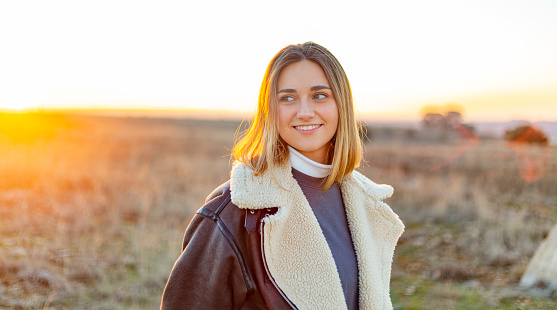 Castilla La Mancha, Spain. Waist-up view of a smiling young woman in a rural environment at sunset