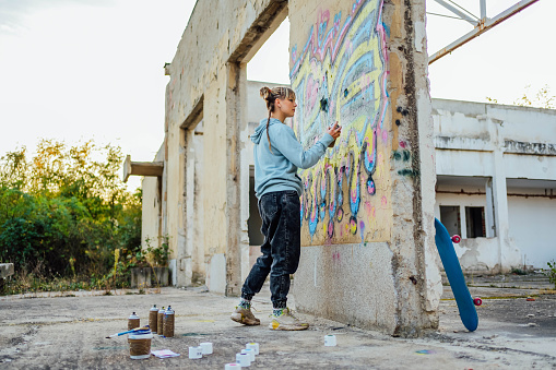 Young woman creating graffiti on the wall
