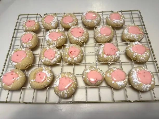 Homemade pink-lemonade thumbprint cookies on cooling rack