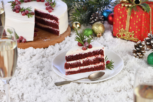 Red Velvet Cake is a traditional red chocolate cake topped with white buttercream and decorated with a Christmas wreath of candied cranberries and rosemary.