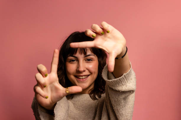 istock Young woman making a frame with her fingers, on a pink background 1831097449