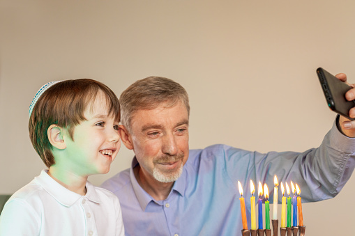 A 50 year old man and his 6 year old son celebrate Hanukkah in their home