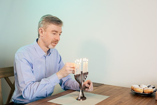 A 50 year old man celebrates Hanukkah at home