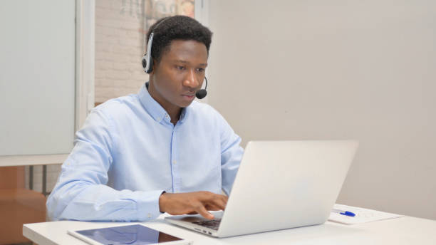 istock African Man with Headset Working on Laptop in Call Center 1831109210