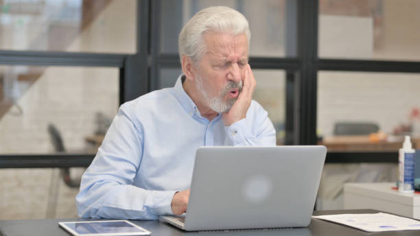 istock Old Businessman with Toothache Working on Laptop in Office 1831116053