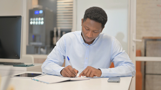African Businessman Writing a Letter in Office