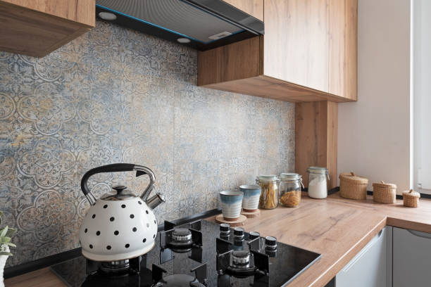 istock Modern kitchen with wooden furniture, pattern tile, and ceramic stove top with kettle. 1831137808