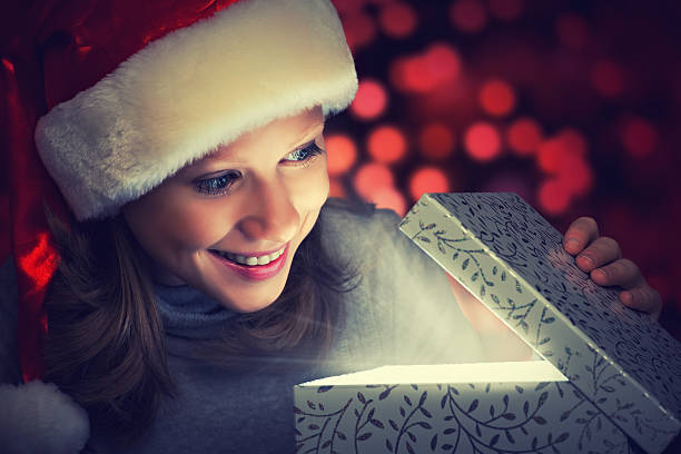 istock happy woman in a Christmas cap opens the magic box 183114287