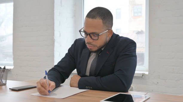 istock Mixed Race Businessman Writing a Letter in Office 1831150029