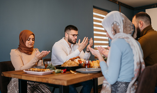 Traditional Muslim family sharing pita bread during dinner on Ramadan