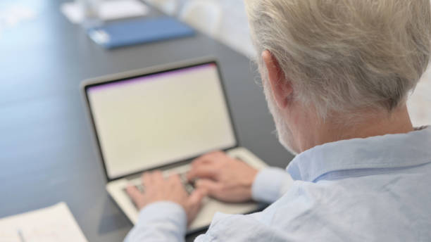 istock Rear View of Old Man Typing on Laptop 1831155339