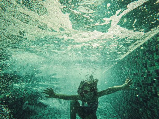 Cute little girl having fun underwater in the swimming pool.