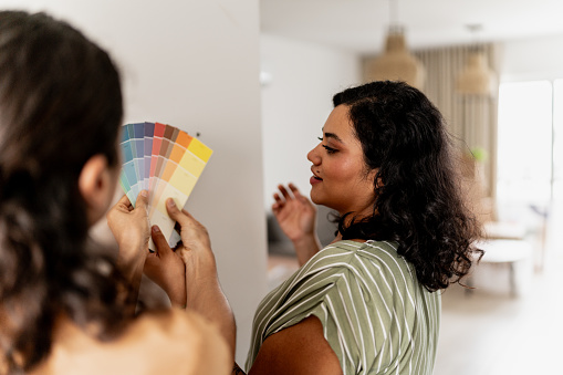Young woman talking with her husband to choose the color swatch of the wall at home