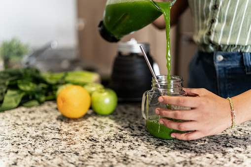 Close-up of a woman preparing detox juice in kitchen at home