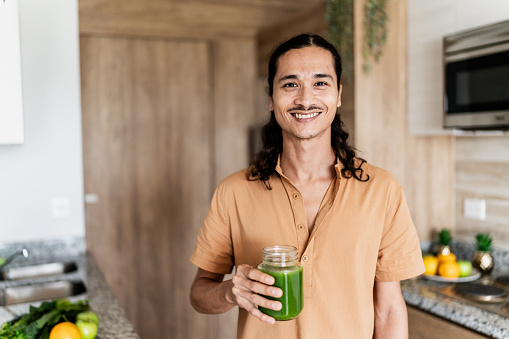 Portrait of a mid adult man holding detox juice at home