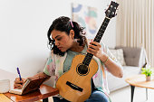 Young woman writing song lyrics at home
