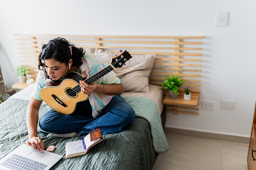 Young woman using computer in bedroom at home