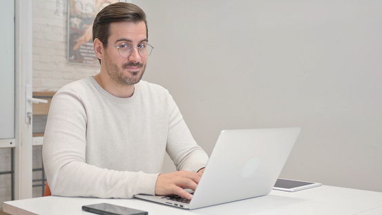 Middle Aged Man Shaking Head in Approval at Camera in Office