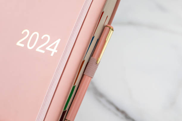 istock Pink coral colored diary for the year 2024, pen, marble background 1831199586