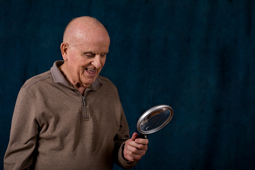 Healthy and vibrant 90 year old examining through a magnifying glass.