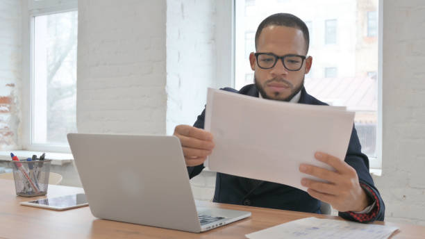 istock Mixed Race Businessman Working on Documents and Laptop 1831227191