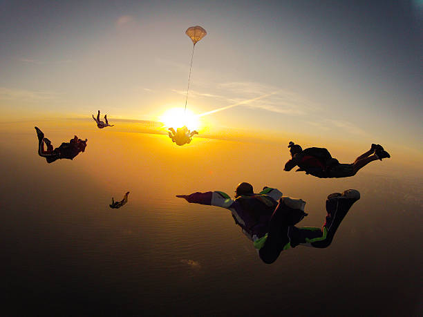 Group of people skydiving at sunset Tandem Skydive during sunset, with 5 other skydivers in proximity. skydiving stock pictures, royalty-free photos & images