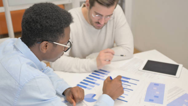 istock Mixed Race Business People Discussing Business Report 1831234954
