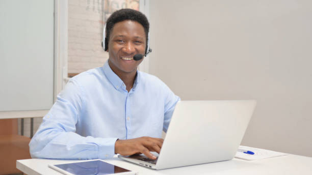istock Smiling African Man with Headset Looking at Camera in Call Center 1831236981