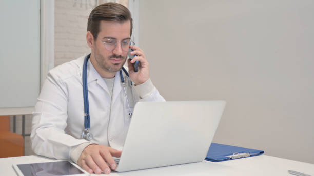 istock Middle Aged Doctor Talking on Phone in Clinic 1831240140