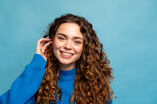 Portrait of a beautiful young woman with curly hair on a blue background