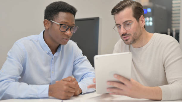 istock Close up of Mixed Race People Discussing Project on Tablet 1831266703