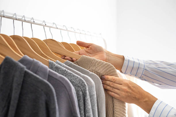 istock Women's hands choose neutral clothes from a hanger. White, beige and gray jersey. 1831275148