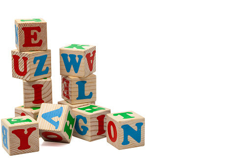 Wooden children's play cubes with blue, red and green letters in the shape of turrets stand one on top of the other and lay side by side. Isolate.
