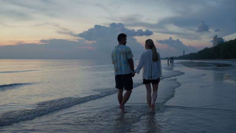 Young couple walking on the beach at sunset.