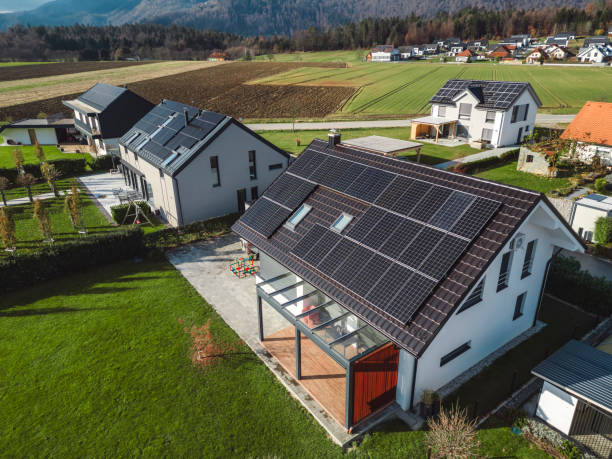 Low aerial close view new dense rural housing development, mostly grey roofing, some green landscaping, young trees. Modern homes with flat roof