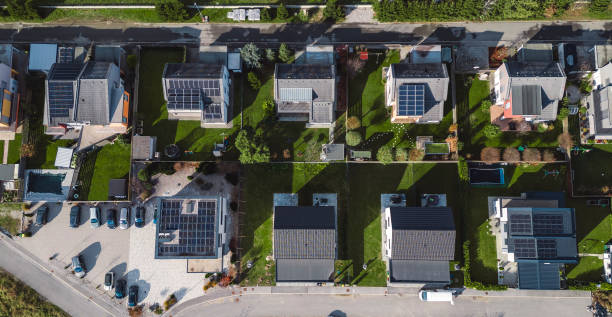 Low aerial close view new dense rural housing development, mostly grey roofing, some green landscaping, young trees. Modern homes with flat roof