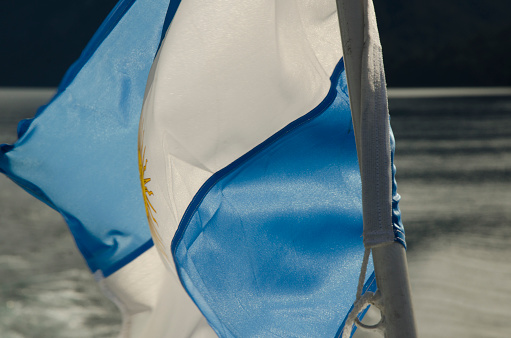 light blue and white flag waving with water in the background, flag of Argentina