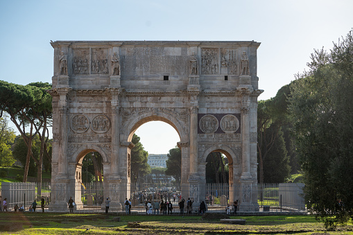 Rome, Italy: 2023 November 13: Tourists at the Arch of Constantine. Triumphal arch and Colosseum in the background in Rome, Italy in 2023.