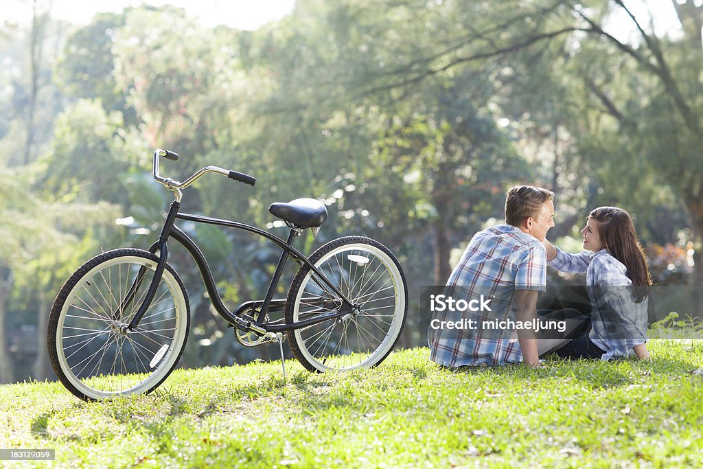 teen couple sitting on the grass cute lovely teen couple sitting on the grass outdoors Adolescence Stock Photo