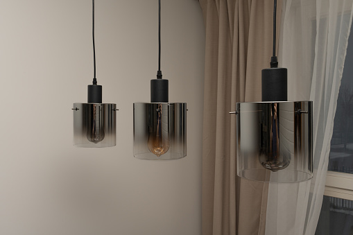 Three hanging lamps in the form of a cylinder with tinted glass.