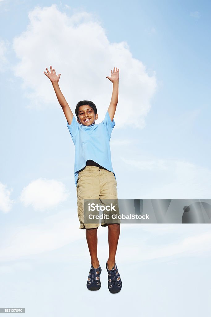 Joyeuse jeune garçon sautant avec les bras écartés contre ciel - Photo de Activité libre de droits