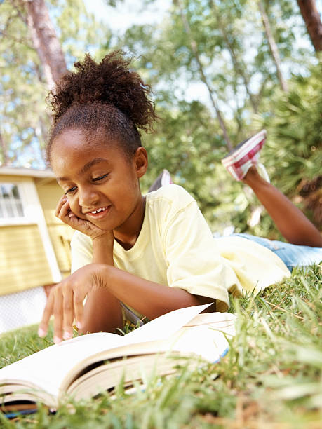 istock An African American girl reading book while lying on lawn 183137525