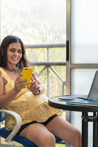 A mother-to-be using her cell phone at home