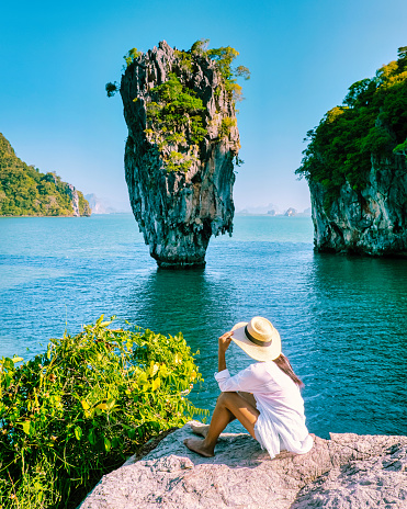woman on vacation in Thailand visit Phangnga Bay Thailand James Bond Island, Asian woman with hat on a trip to James Bond Island in Phannga bay on a sunny day