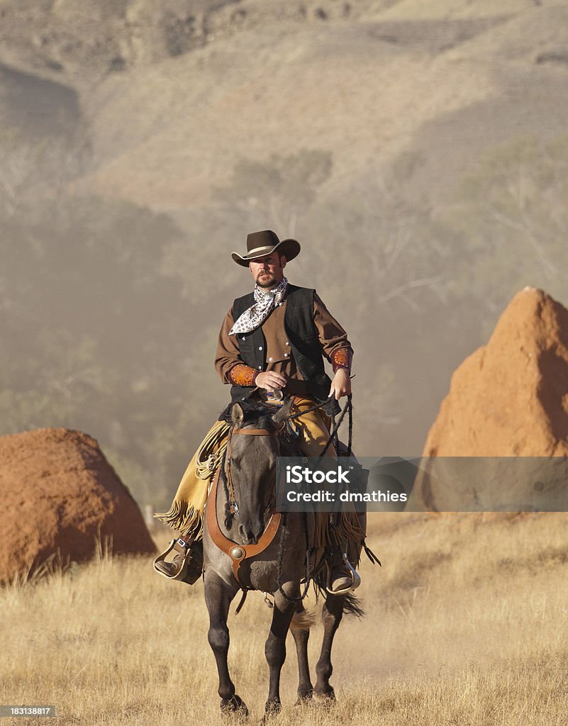 Ковбой едет лошадь между два больших валунов - Стоковые фото Ковбой роялти-фри