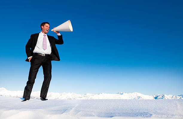 de negócios a gritar no topo de uma montanha caped inverno neve - winter public speaker megaphone snow - fotografias e filmes do acervo